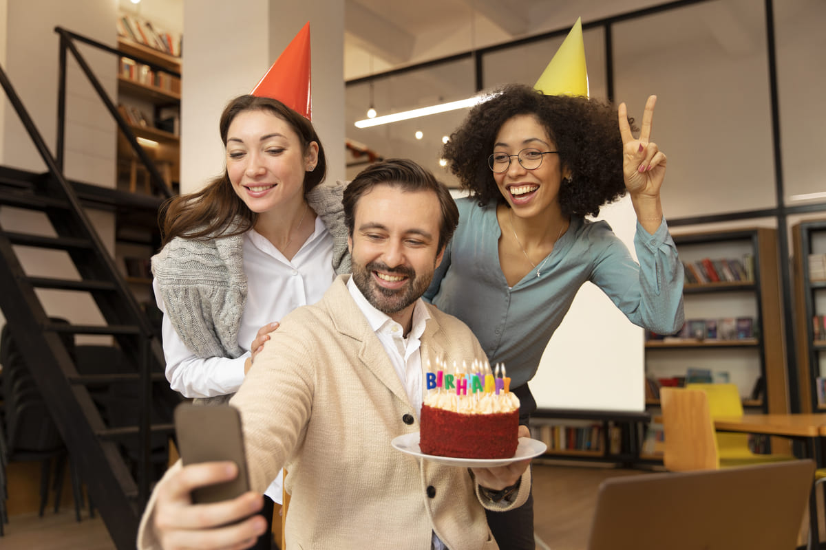 Pessoas celebrando com um bolo e chapéus de festa durante um momento descontraído, refletindo a ideia de um Day Off de aniversário.